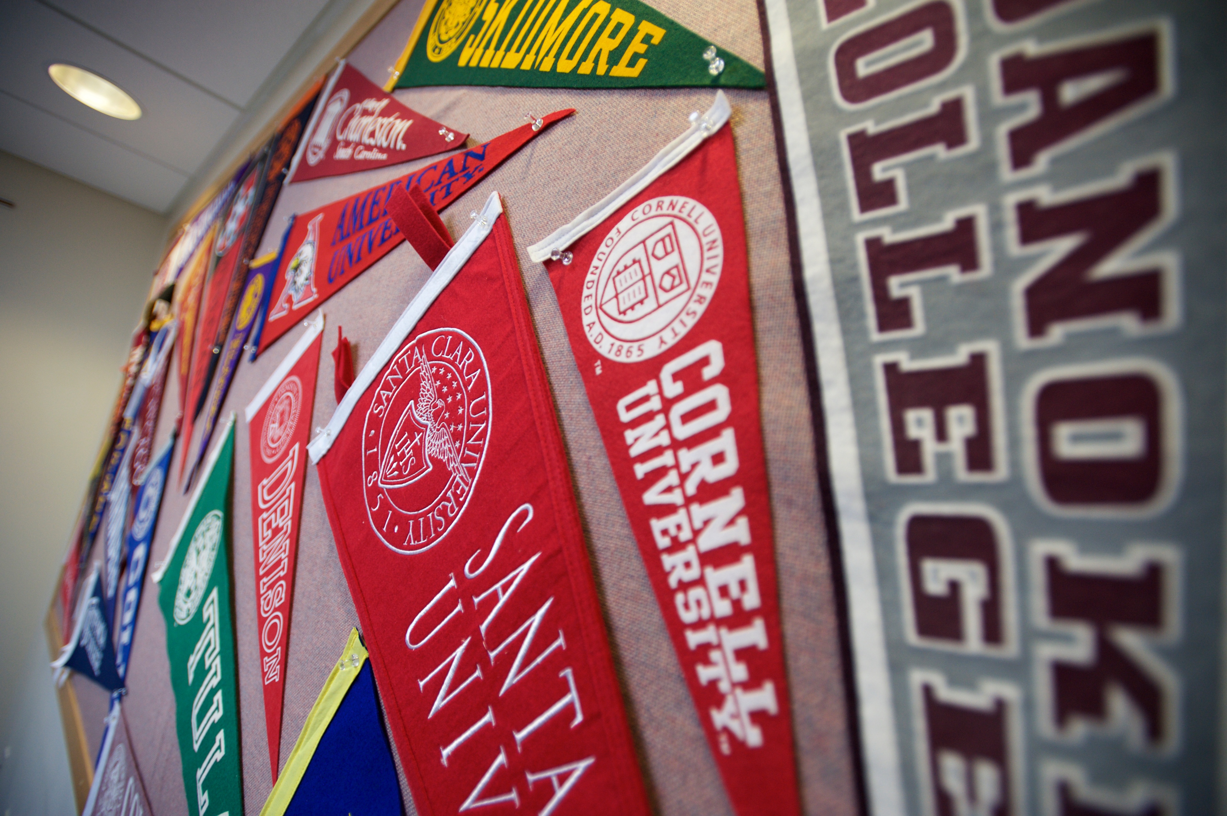 Variety of college and university pennants hung on a wall 